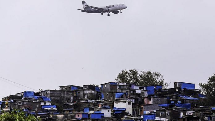 A plane flies over Mumbai slums | Dhiraj Singh/Bloomberg