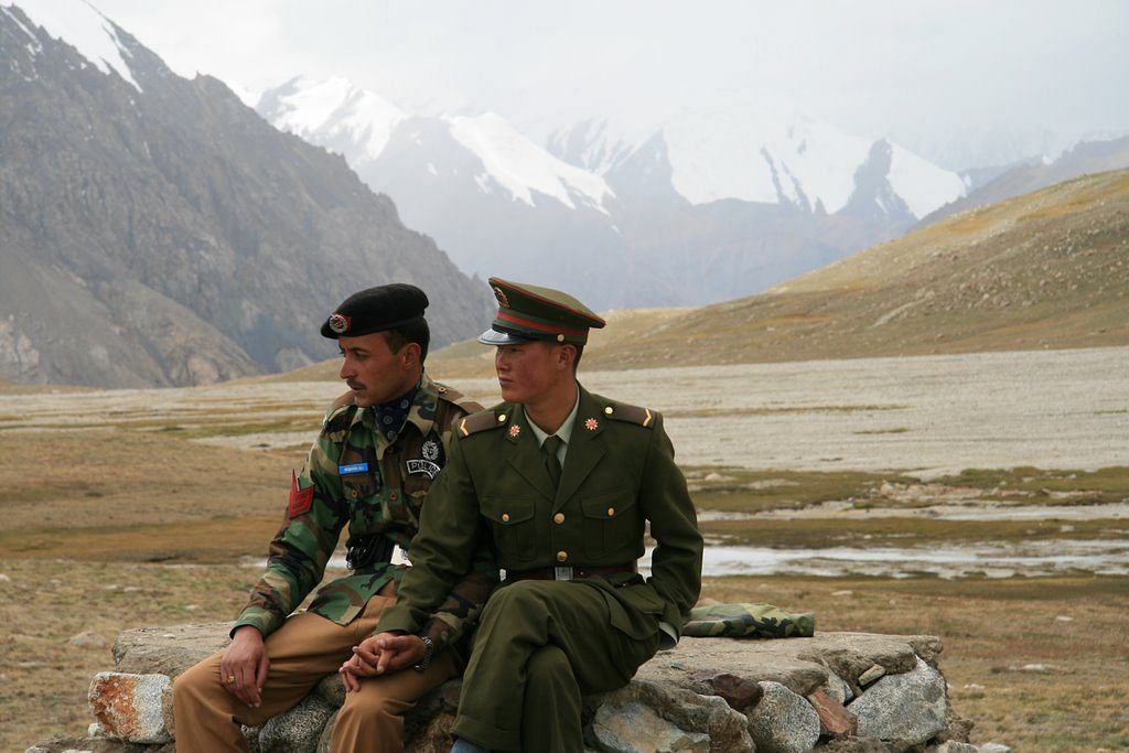 Chinese and Pakistani guards sitting on a rock at the Khunjerab Pass