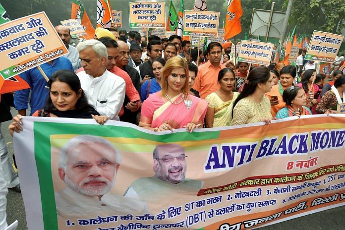 BJP workers display a banner during their Anti-black Money Day rally to mark the first anniversary of 'Demonetisation' announcement in New Delhi on Wednesday.