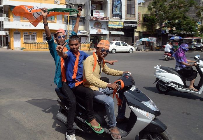 Indian Bharatiya Janata Party (BJP) supporters celebrate victory at a busy intersection in Gujarat
