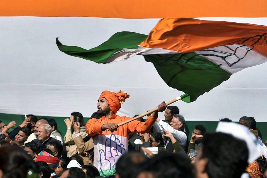 A Congress party spokesperson waves the party flag during a ceremony