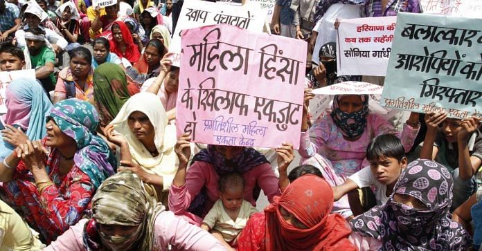 Women sitting in protest with written slogans to stop crime against