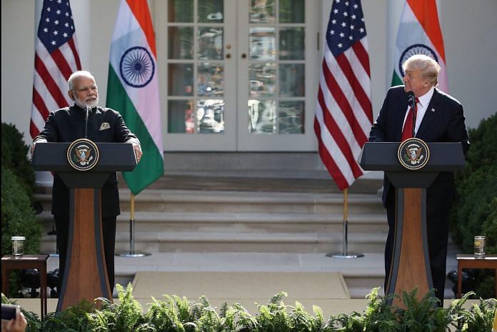 Donald Trump and Narendra Modi standing in front of podiums, with the flags of The USA and India behind them.