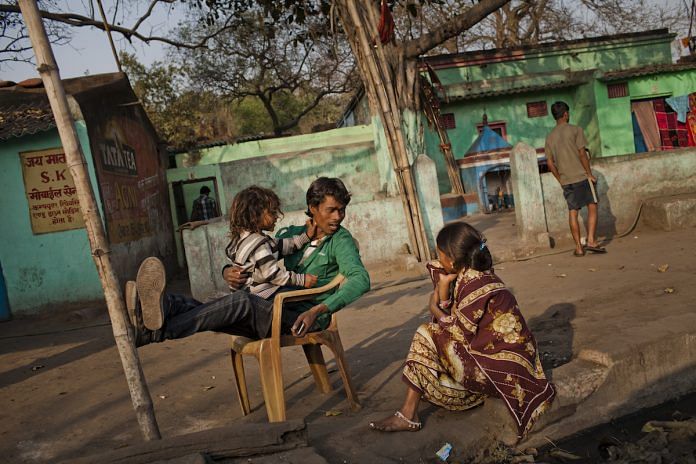 A villager sits with his family in the village of Guhanwadi near Jharia in Jharkhand