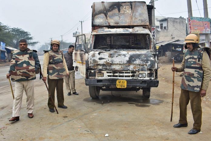 Police personnel inspect a burnt truck