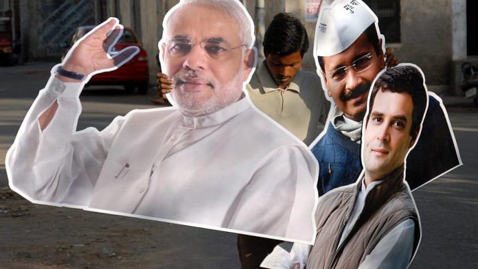 An Indian worker holds cut-outs Narendra Modi, Rahul Gandhi, and Arvind Kejriwal