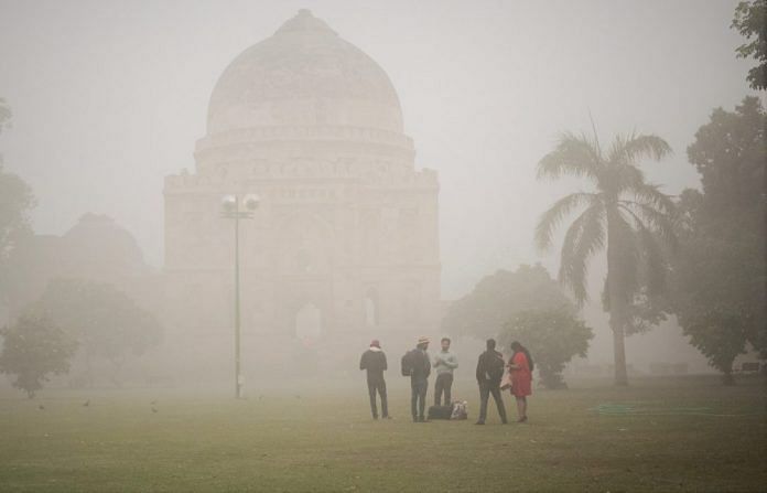 People stand in a park amid heavy dust and smog in Delhi