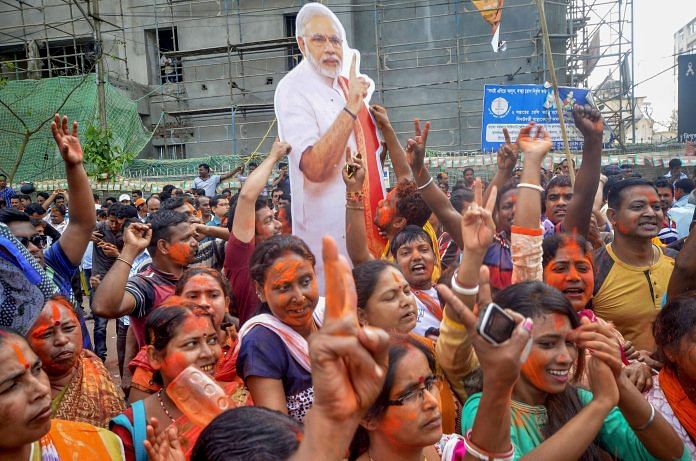 BJP supporters hold up a placard of Narendra Modi after party's victory in Tripura | PTI