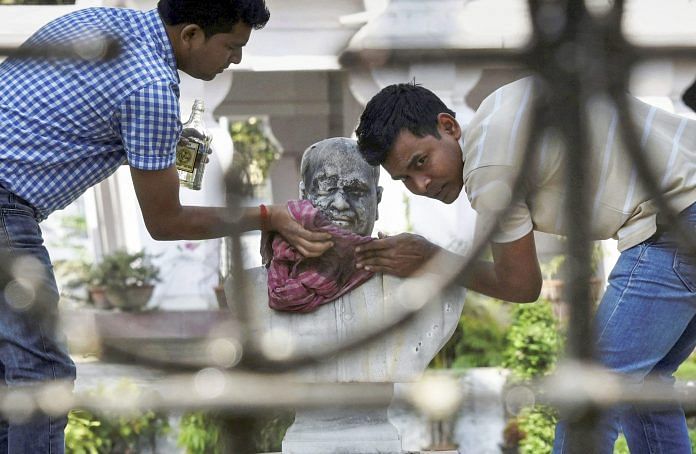 A group of people clean the bust of Bharatiya Jana Sangh founder Syama Prasad Mukherjee after it was vandalised | PTI