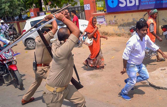 Police personnel lathicharge on an activist during the 'Bharat Bandh' by Dalit organisations, in Varanasi Monday. | PTI