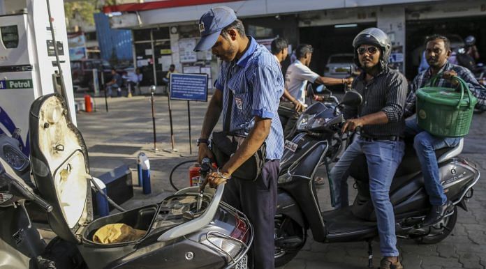 A worker refuels a scooter | Dhiraj Singh/Bloomberg
