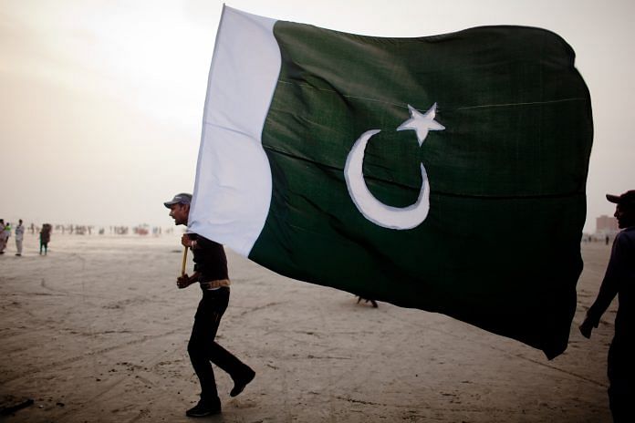 A man walks with a Pakistan National flag | Daniel Berehulak/Getty Images