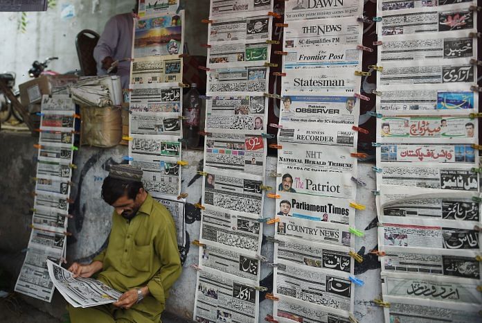 A Pakistani man reads a newspaper | FAROOQ NAEEM/AFP/Getty Images