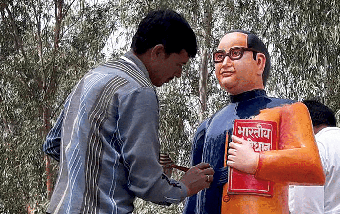 A BSP worker paints the newly constructed statue of BR Ambedkar in blue in Badaun