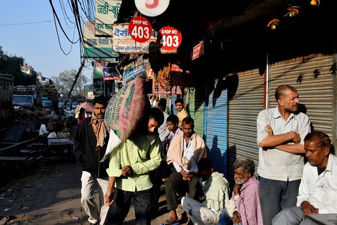 Men waiting outside shops for work in New Delhi during the demonetisation period in India | Bloomberg