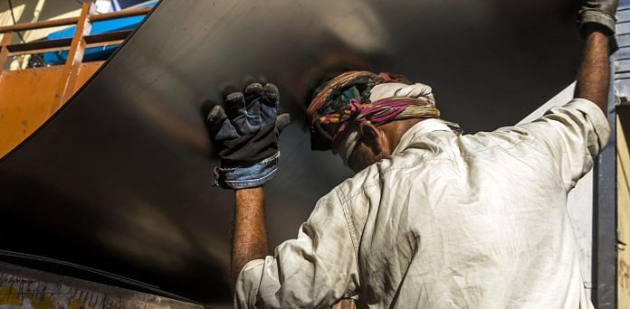 A workers loads a steel sheet onto a truck in the Naraina steel and iron market area of New Delhi, India