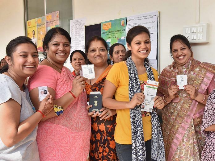 Voters show their voting ID as they cast their vote for Karnataka Assembly elections in Hubballi on Saturday