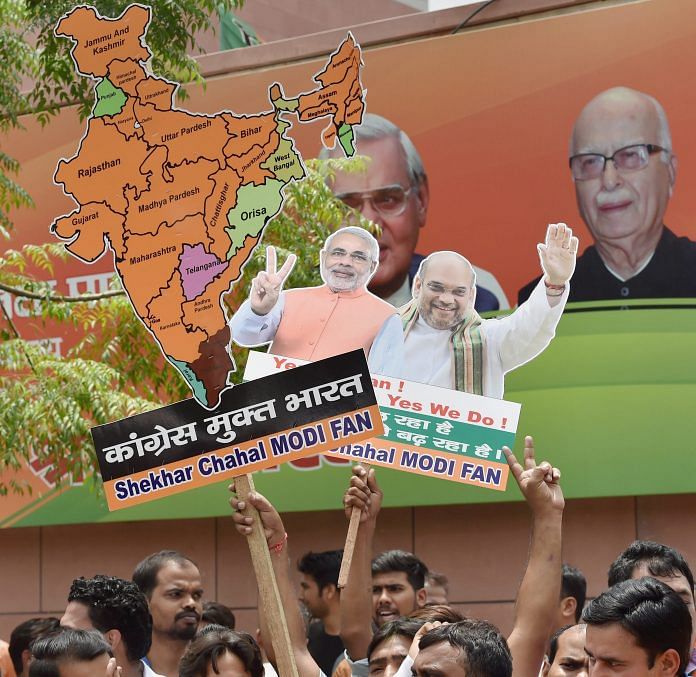 BJP workers display the cut-outs of PM Narendra Modi and party President Amit Shah as they celebrate party's decisive lead in Karnataka Assembly elections, as the counting of votes is in progress, outside the party headquarters in New Delhi on Tuesday
