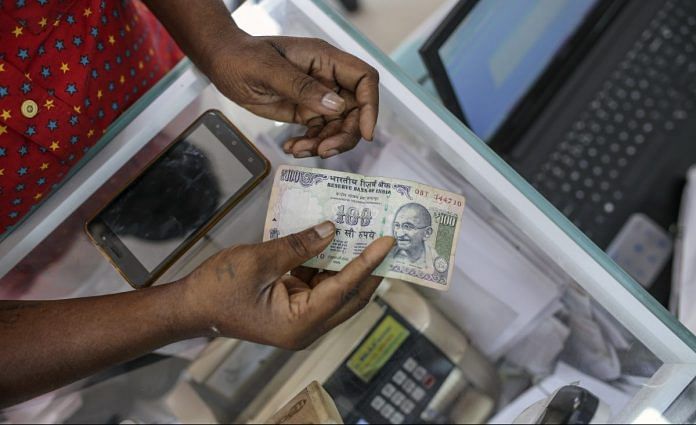 A customer holds Indian one hundred rupee banknote in India | Dhiraj Singh/Bloomberg