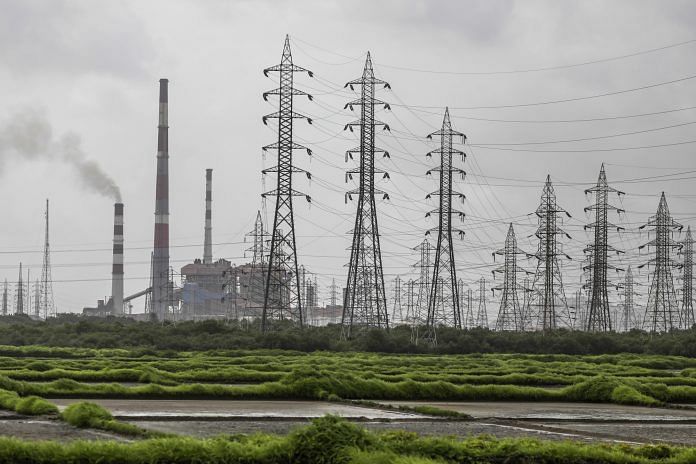 Smoke rises from a chimney as electricity pylons stand at the Tata Power Co. Trombay Thermal Power Station