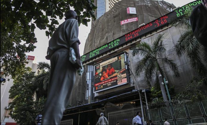 A man looks up at an electronic ticker board that indicates stock figures at the Bombay Stock Exchange (BSE)