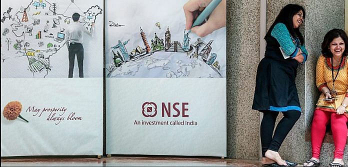 Employees stand next to an advertisement for the National Stock Exchange (NSE) during a break at the bourse in Mumbai