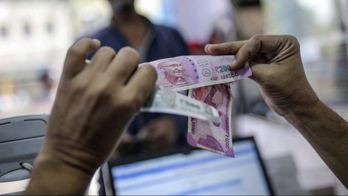 A cashier examines Indian rupee banknotes at the Mayuresh Watches and Traders watch and mobile phone store in the Byculla area of Mumbai