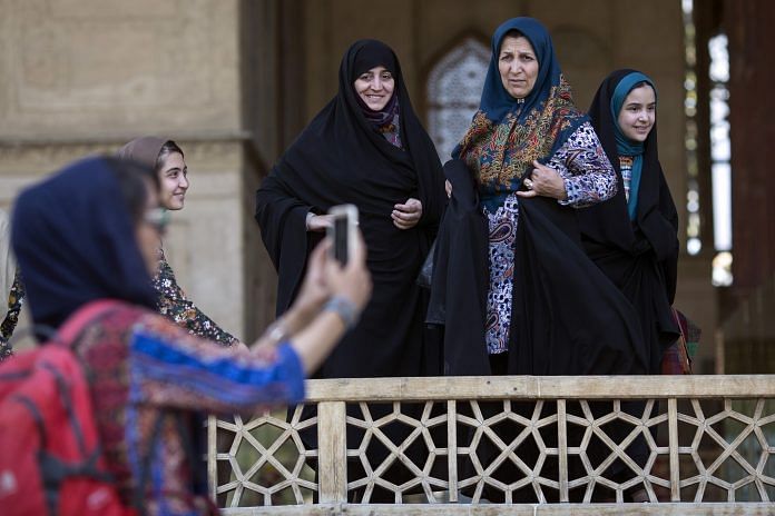 Iranian women watch as a girl clicks selfie at the Chehel Sotun palace in Isfahan, Iran
