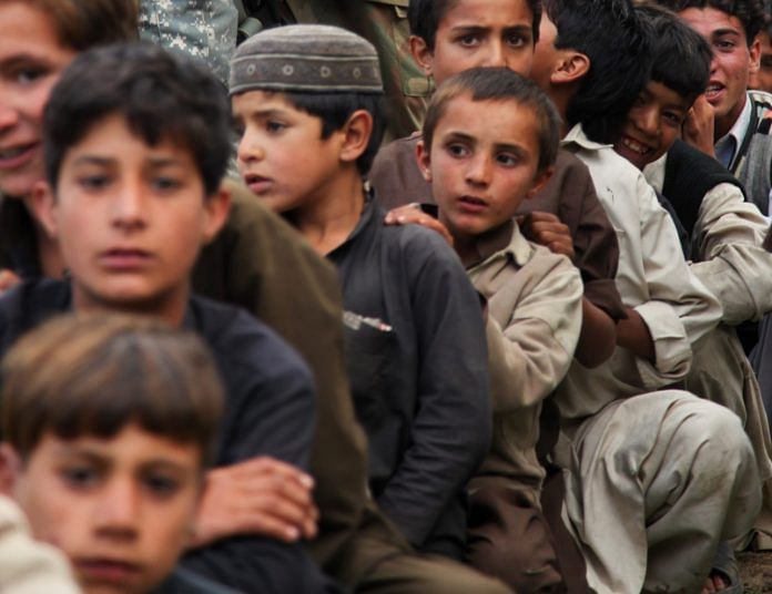 Pakistani children in a queue waiting to be moved after the flood drove many people out of their homes.