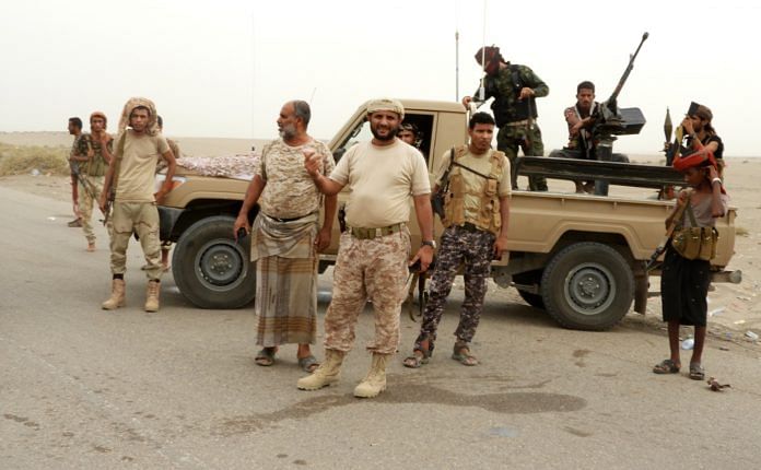 Yemeni pro-government forces stand next to a pickup truck carrying arms along the way to al-Durayhimi district, near Hodeidah