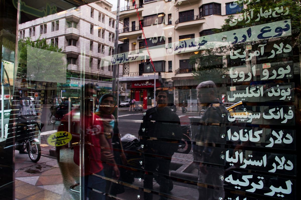Commuters pass a closed currency exchange bureau in Tehran | Ali Mohammadi/Bloomberg