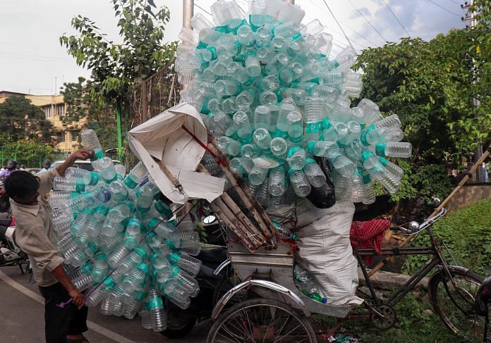 A worker loads a rickshaw with empty plastic water bottles | PTI