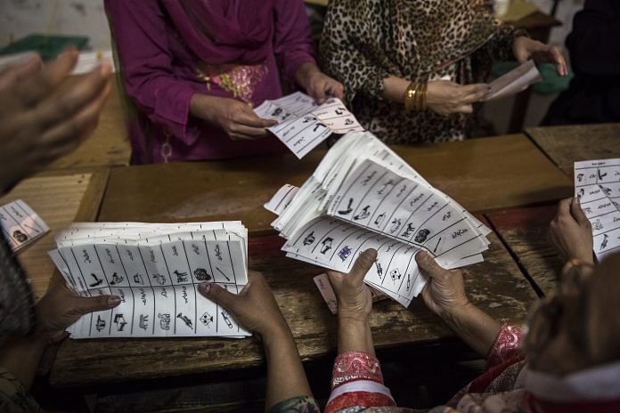 Pakistani election workers count ballots at a polling station