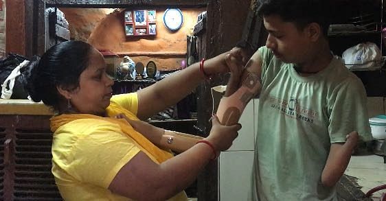 Ritik's mother helps him attach prosthetic arm in their home in Delhi | Image by Shahbaz Ansar, ThePrint