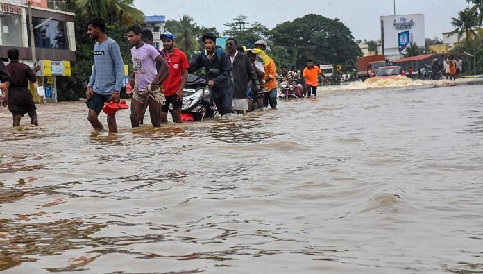 People wading across a waterlogged street in Kochi | ThePrint.in