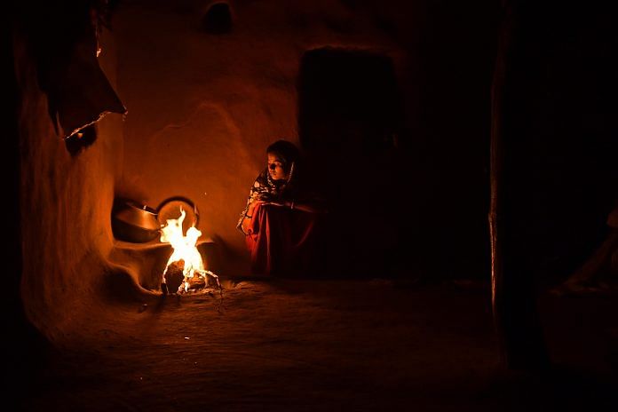 A woman cooks food by fire inside a home in Kraska village, Rajasthan | Anindito Mukherjee/Bloomberg