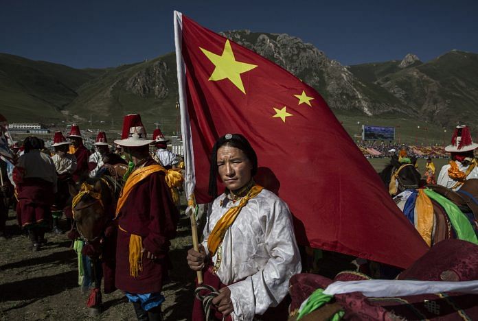 A Tibetan man holds a Chinese flag in Tibetan Plateau in Yushu County, Qinghai, China | Kevin Frayer/Getty Images