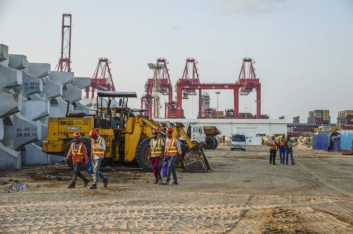 Workers walk past excavators at the site of Colombo Port City, developed by China Harbour Engineering Co