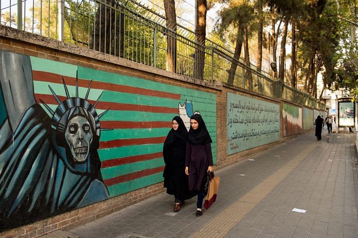 Two Iranian women walk past an anti-American wall mural outside the former U.S. embassy