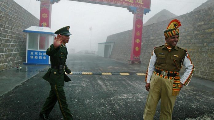 A Chinese soldier and an Indian soldier stand guard at the Chinese side of the Nathu La border | Getty Images