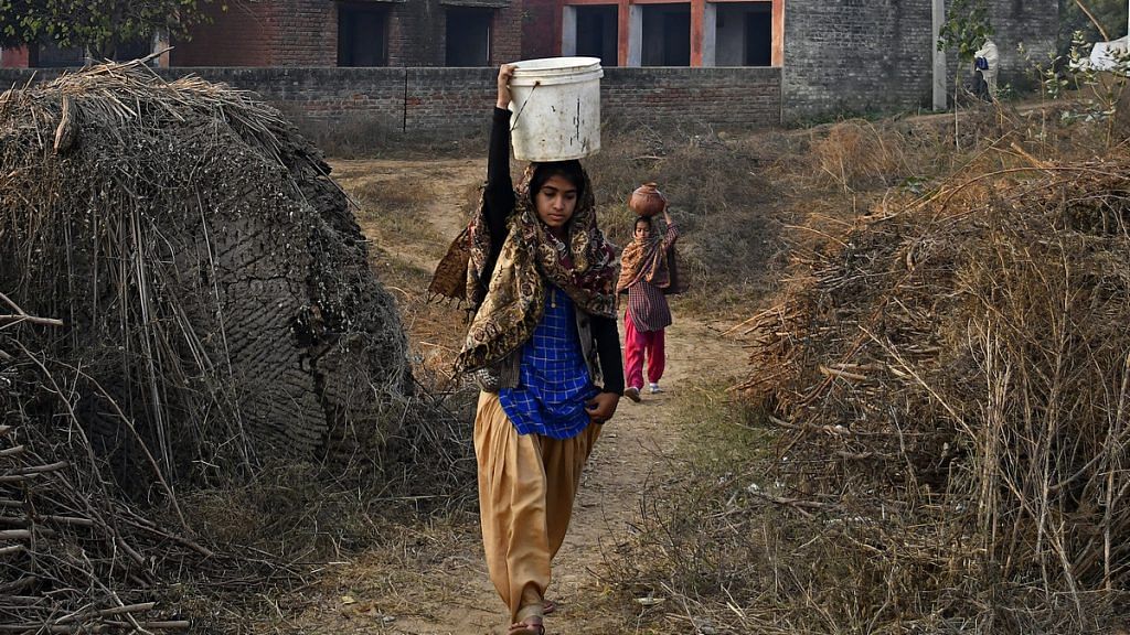 Women carry vessels of drinking water along a track in Haryana | Anindito Mukherjee/Bloomberg