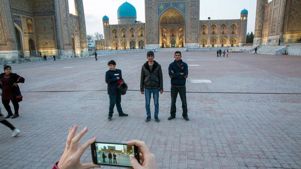 Visitors pose for a photograph at Registan Square in Samarkand, Uzbekistan | Taylor Weidman/Bloomberg