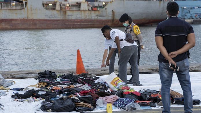 Search and rescue team members look at debris recovered from the crash site on the dockside at Tanjung Priok Port in Jakarta, Indonesia