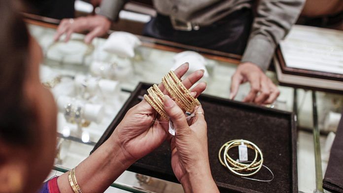 A woman tries on gold bangles at a jewellery store | Representational image | Photo: Dhiraj Singh | Bloomberg
