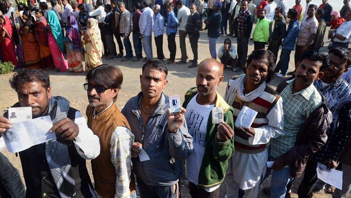 People wait with their identity cards to cast their votes for the Assembly elections, in Jabalpur, Madhya Pradesh
