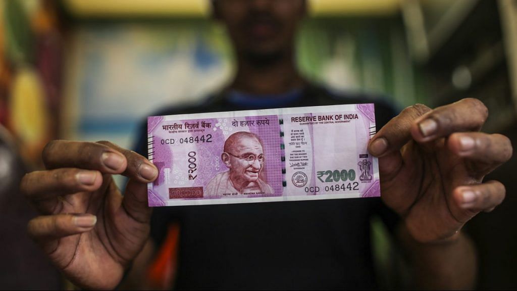 A man holds a Rs 2000 banknote | Dhiraj Singh/Bloomberg