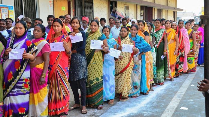 Voters stand in a queue at a polling station to cast their votes for the 2nd phase of Assembly elections in Raipur | PTI