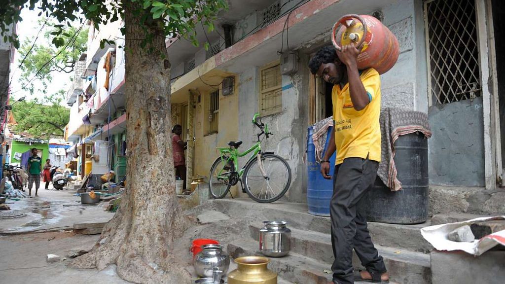 An Indian LPG vendor carries a empty cooking gas cylinder | Noah Seelam/AFP/Getty Images