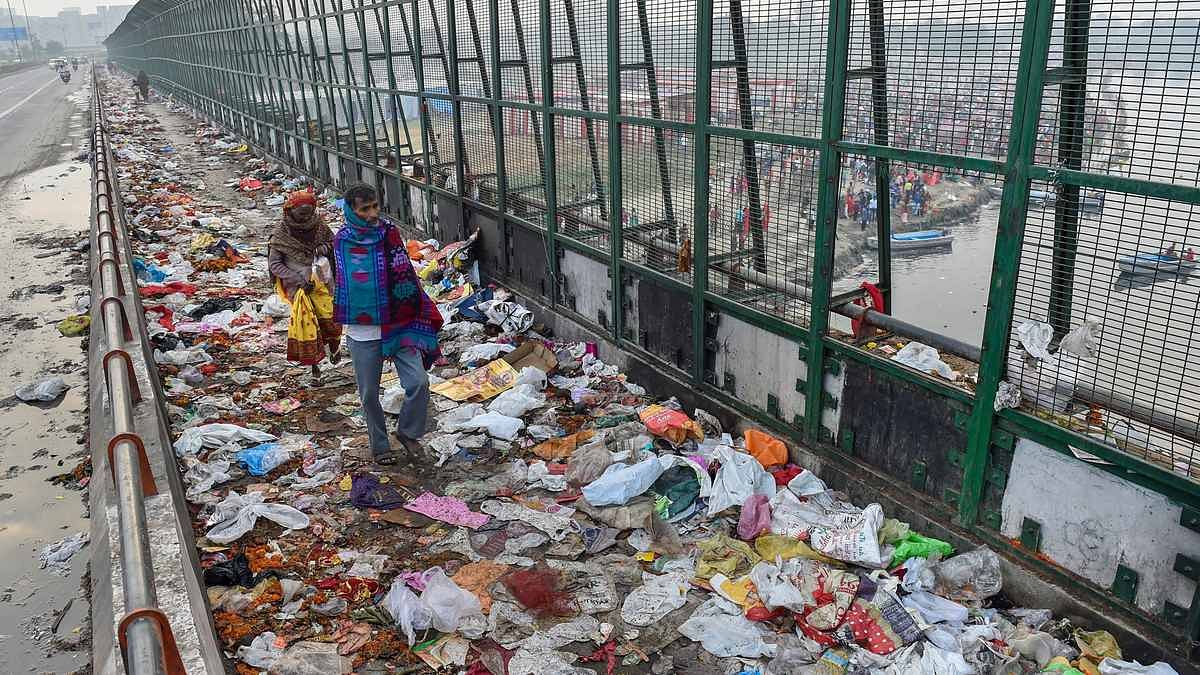 Pedestrians walk over plastic bags scattered on the pavement along Geeta Colony Setu over the River Yamuna, in New Delhi