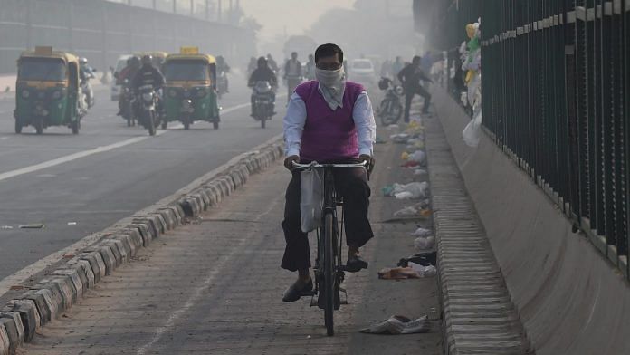 A cyclist protects himself with a handkerchief against air-pollution as he rides through smog, at ITO Bridge in New Delhi